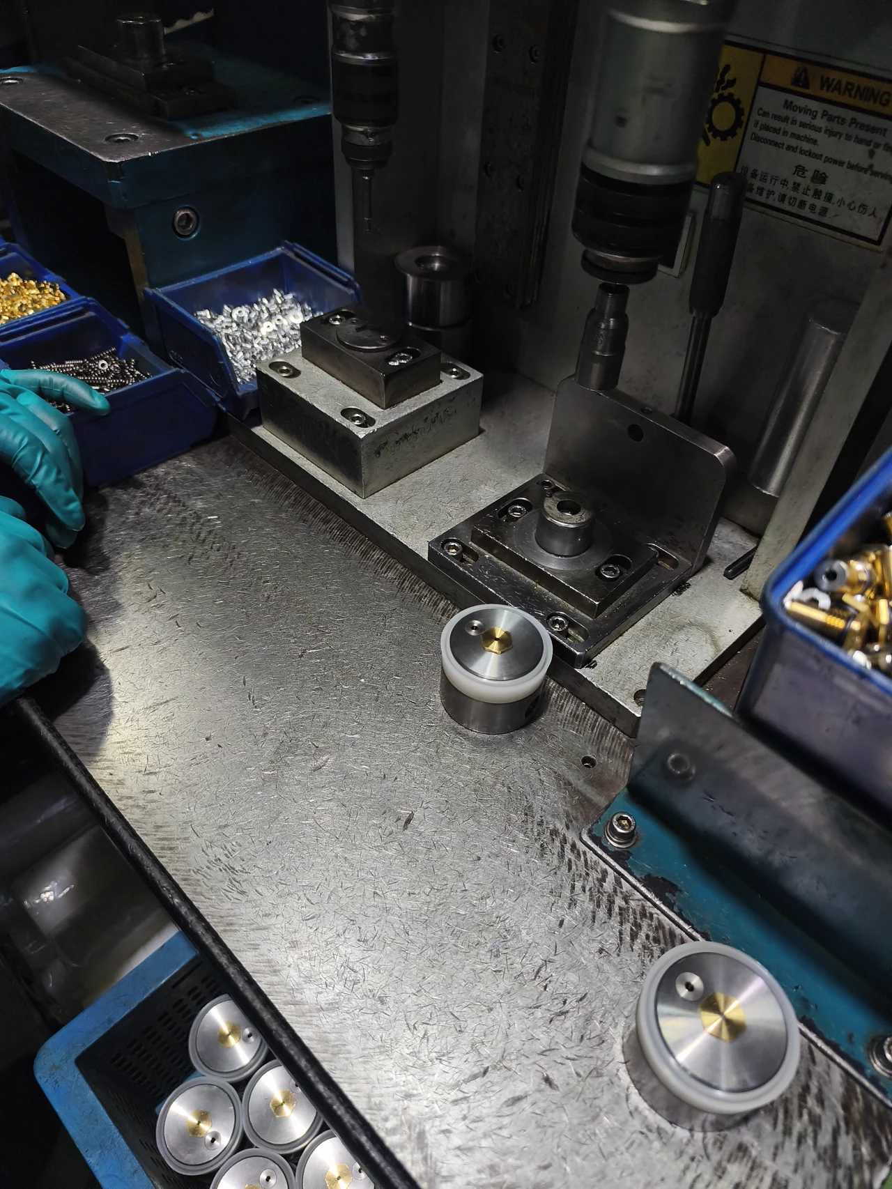 Assembly workstation with component fixtures, parts bins and an operator’s gloved hand.
