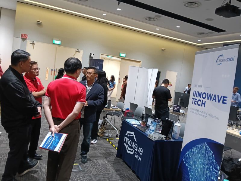 Attendees speaking with the Innowave Tech team beside its event display.
