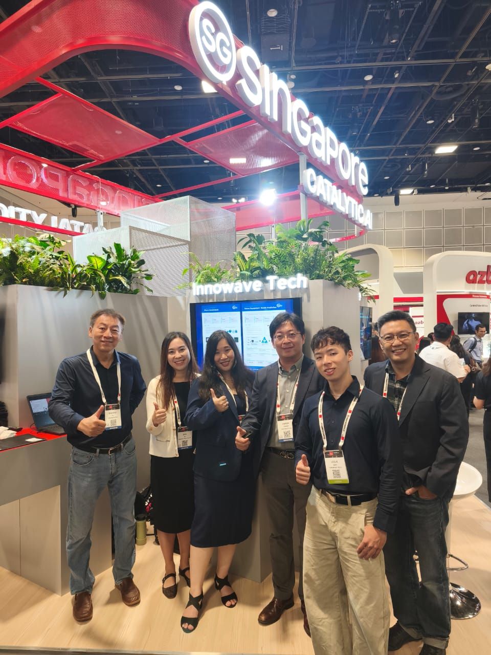 六位 Innowave Tech 团队成员在公司展位合影，上方为 Singapore Catalytic AI 展示标识。